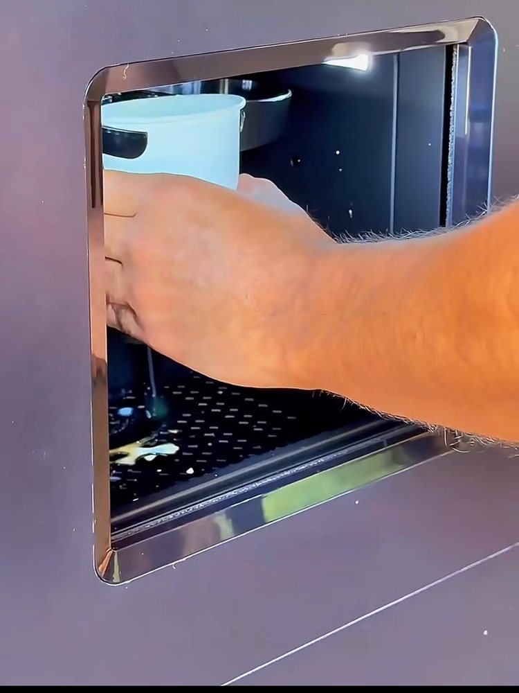 Mão retirando o copo de shake na janelinha da estação NutraStation